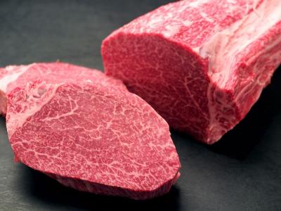 Two pieces of raw beef on a dark surface